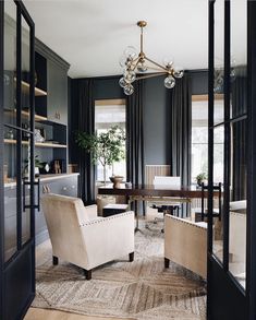 a living room filled with furniture and a chandelier hanging from the ceiling next to a window