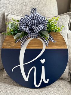 a wooden sign with the letter h on it that has a bow and flowers in it