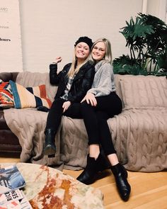 two women sitting on a couch posing for the camera