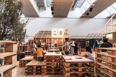 several people working in a large room with lots of wooden pallets on the floor