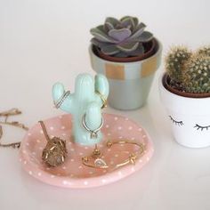 three small cactus plants are sitting next to each other on a pink tray with white polka dots