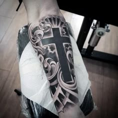 a man's arm with a cross tattoo on it and an ornate design in the middle