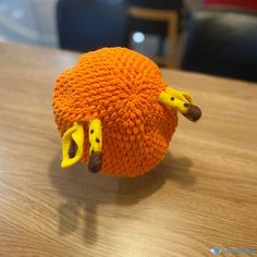 an orange knitted object sitting on top of a wooden table