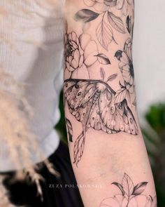 a woman's arm with a butterfly and flowers tattoo design on the left forearm