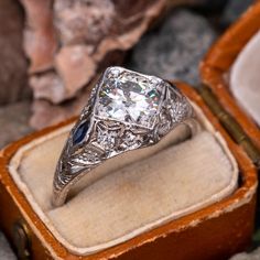 This magnificent circa 1920s Art Deco engagement ring is centered with one (1) old European cut diamond weighing 1.47 carat and bead set into a square shaped head. The ring features a pierced design, bordered with milgrain edging and accented with engraved wheat motifs. The ring measures 12.5mm at the top, rises 6.3mm above the finger, tapering to 1.6mm wide and 1.1mm thick at the base of the shank. The ring is currently a size 9 and we offer complimentary resizing to fit. Art Deco Jewelry Rings 1920s, Art Deco Square Cut Diamond Wedding Ring, Art Deco Diamond Ring With Square Cut For Wedding, Classic Square Cut Platinum Wedding Ring, Art Deco Square Cut Diamond Jewelry, Art Deco Diamond Ring With Radiant Cut, Art Deco Asscher Cut Diamond Jewelry, Art Deco Asscher Cut Wedding Ring With Center Stone, Art Deco Asscher-cut Wedding Ring With Center Stone