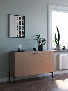 a living room with a plant on top of a cabinet next to a radiator