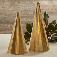 two gold christmas trees are sitting on a table