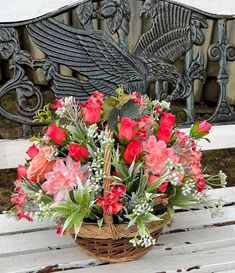 a basket filled with flowers sitting on top of a wooden bench