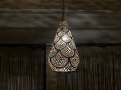 a light hanging from the ceiling in a room with curtains and drapes behind it