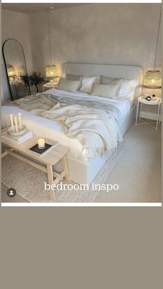 a white bed sitting in a bedroom next to two tables with candles on top of it