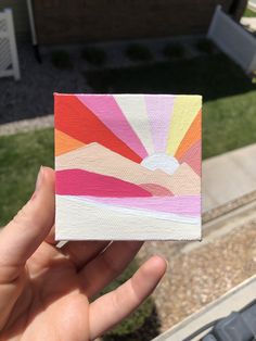 someone is holding up a piece of paper that has been painted with different colors and shapes