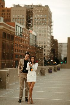 a man and woman standing in an empty parking lot with rain falling down on them