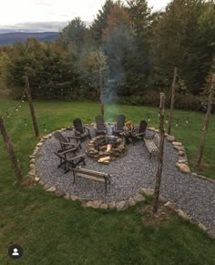 an outdoor fire pit surrounded by chairs and trees