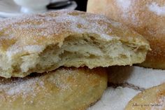 several donuts with powdered sugar are stacked on top of each other in front of a cup and saucer