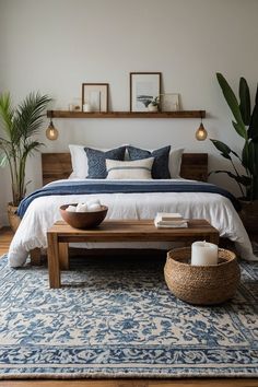 a bedroom with a bed, table and plants on the wall next to each other