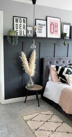 a bedroom with gray walls and pictures on the wall above the bed, along with a rug