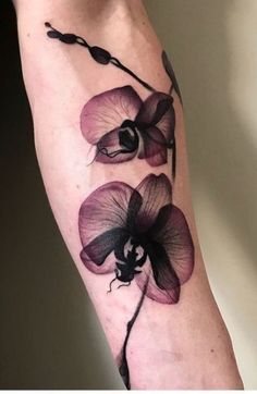 a woman's arm with purple flowers on the left side of her body and an insect in the middle