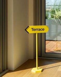 a yellow sign sitting on top of a wooden floor next to a window and door