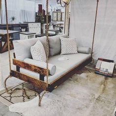 a swing bed with pillows on it in a room filled with furniture and decor items