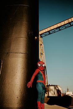 a spider man standing next to a large black object