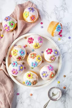 a white plate topped with cupcakes covered in frosting and sprinkles