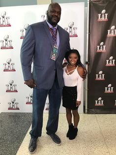 a man standing next to a woman in front of a red carpeted wall with an american football logo on it