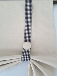 a black and white checkered tie is hanging on the back of a window curtain