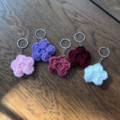 four crocheted flower key chains on a wooden table