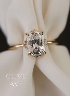 an engagement ring with a cushion cut diamond surrounded by pave diamonds on a white cloth