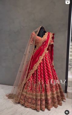 a mannequin dressed in a red and gold lehenga with an attached veil