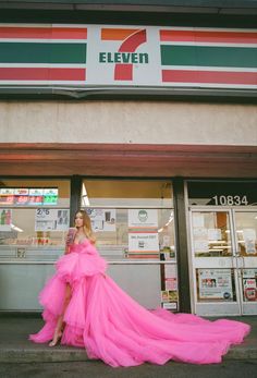 a woman in a pink dress is standing on the steps outside of a store front