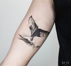 a whale tail tattoo on the left arm