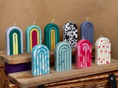 several colorful candles sitting on top of a wooden table next to a wicker basket