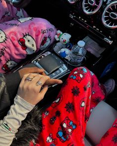 a person sitting in a car holding a cell phone with hello kitty on it's sleeve