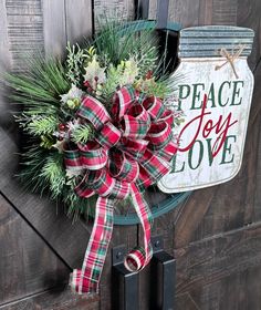 a christmas wreath hanging on the side of a door with a peace joy love sign