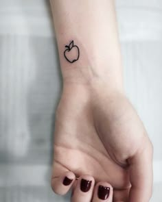 a small apple tattoo on the wrist is shown in black ink, and it looks like an apple