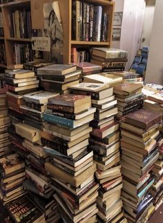 a large stack of books sitting on top of a floor next to a book shelf