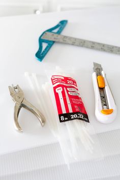 some tools are laying out on a table with measuring tape and scissors next to them