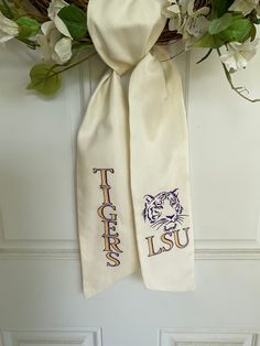 two white scarfs with the letters lsu and tiger on them hanging from a door