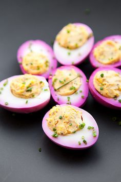 small deviled eggs with mayonnaise and chives on black surface, top view