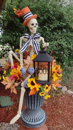 a skeleton sitting on top of a vase filled with sunflowers and a lantern