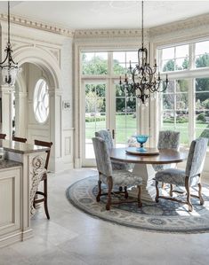 an elegant dining room with chandelier, table and chairs in front of large windows