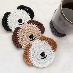 three crocheted coasters sitting next to a cup of coffee