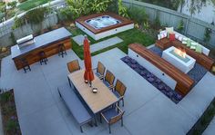 an outdoor hot tub surrounded by wooden tables and chairs in the middle of a yard