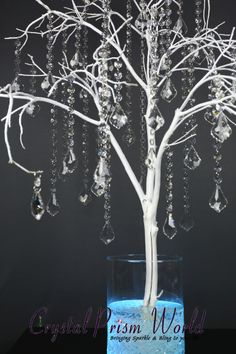 a white tree with crystal hanging from it's branches in a blue glass vase