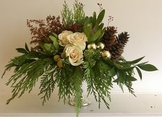 a vase filled with flowers and greenery on top of a table