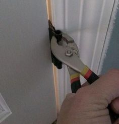 a person is holding a pair of scissors in their hand while they are working on the wall