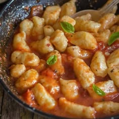 a bowl filled with pasta and sauce on top of a wooden table