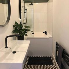 a white bathroom with black and white tile flooring, a large mirror above the bathtub