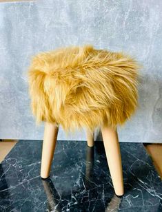 a stool made out of wooden legs and fur on top of a black marble slab